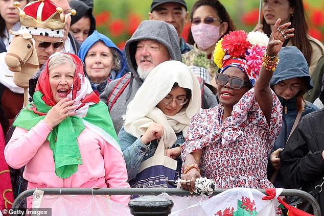 Royal fans try to take cover from the rain ahead of Trooping the Colour in London today