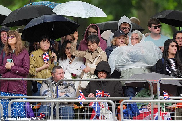 Royal fans try to take cover from the rain ahead of Trooping the Colour in London today