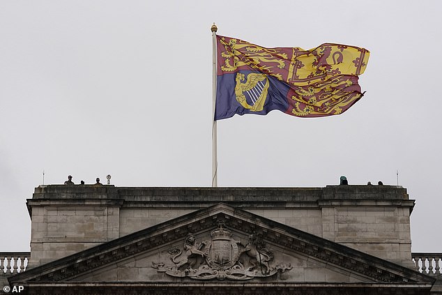 The Royal Standard flag flies above Buckingham Palace as police watch the crowds today