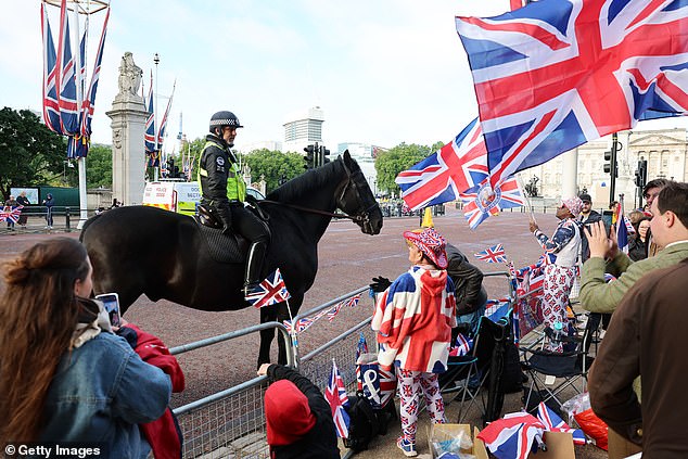 A mounted police officer speaks to royal fans on The Mall ahead of Trooping the Colour today