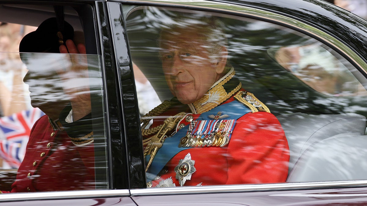 König Charles in einem Auto in roter Uniform
