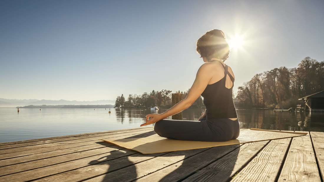 Woman doing yoga exercises by a lake