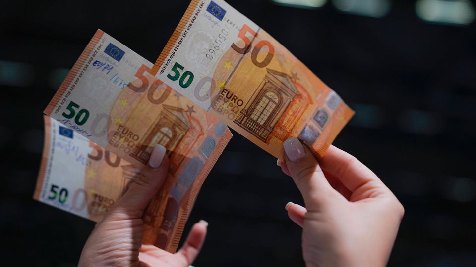 A woman holds a real 50 euro bill in her right hand