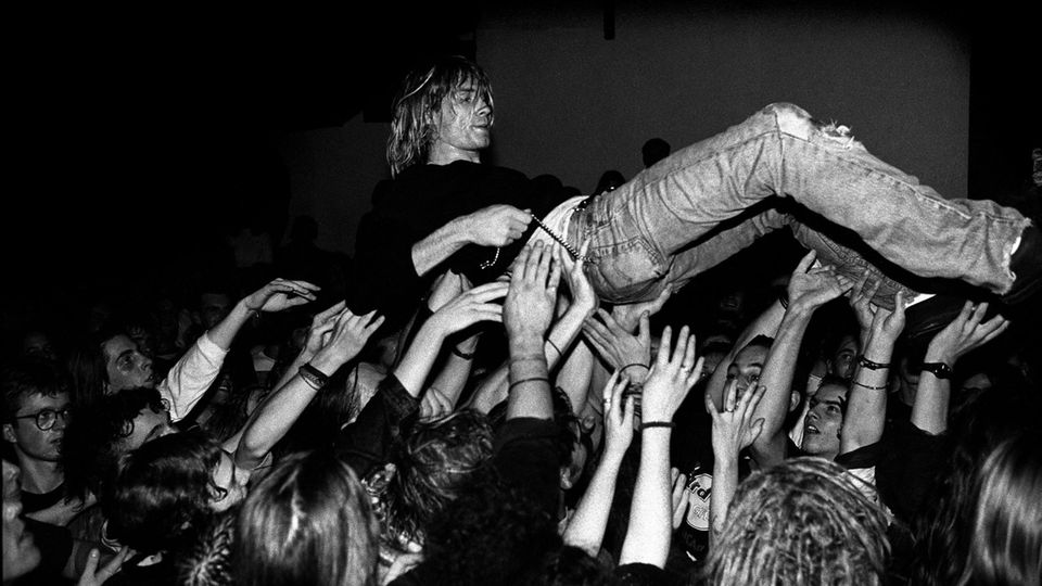 Kurt Cobain is carried in the hands of fans at a concert
