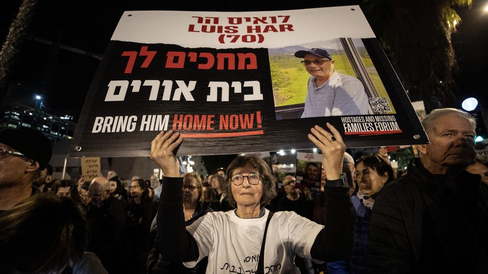A Protestant woman holds up a sign.  It shows the picture of an Israeli hostage held by Hamas