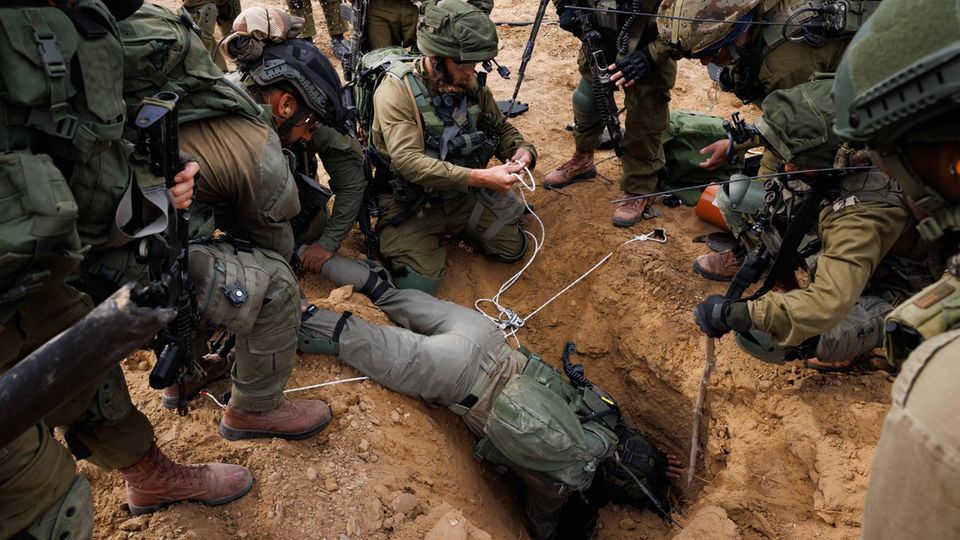 An Israeli soldier leans into a Hamas tunnel entrance