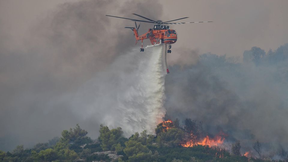 A helicopter drops water over a forest fire in Greece