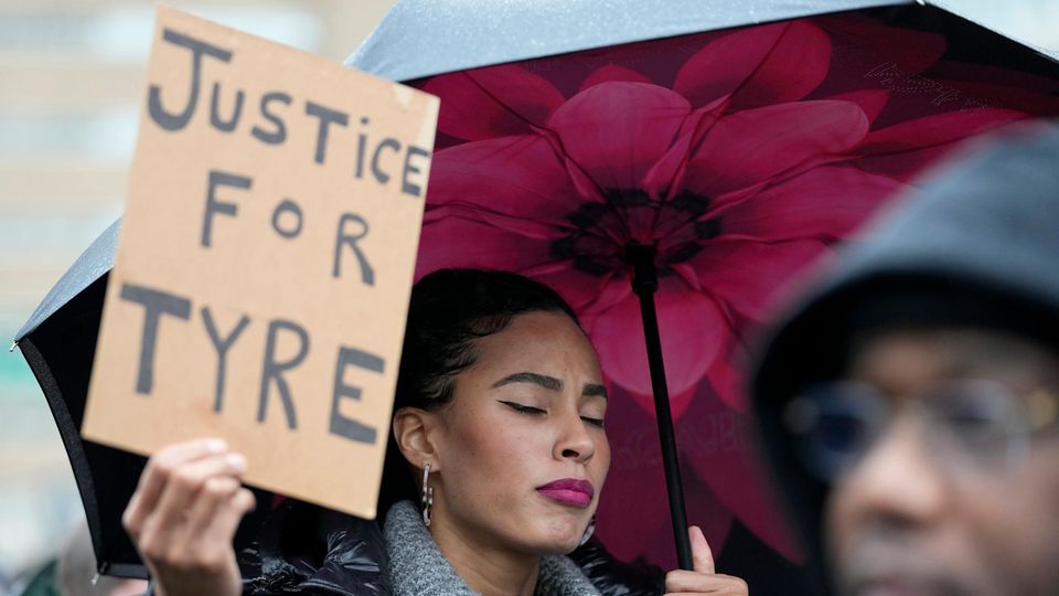 A woman holds a sign that says "Justice for Tire"