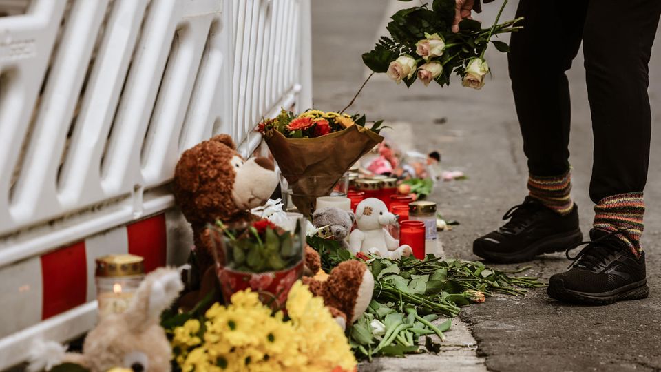A woman places flowers on the barrier in front of a residential building in Solingen where an entire family died