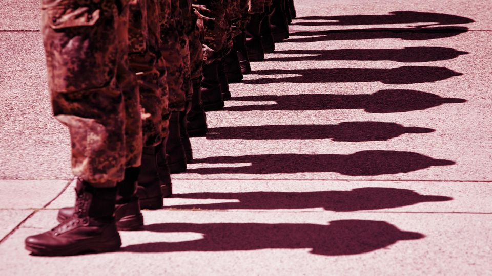 Bundeswehr soldiers stand in a row in uniform, you can see their legs up to the knees and the shadows they cast