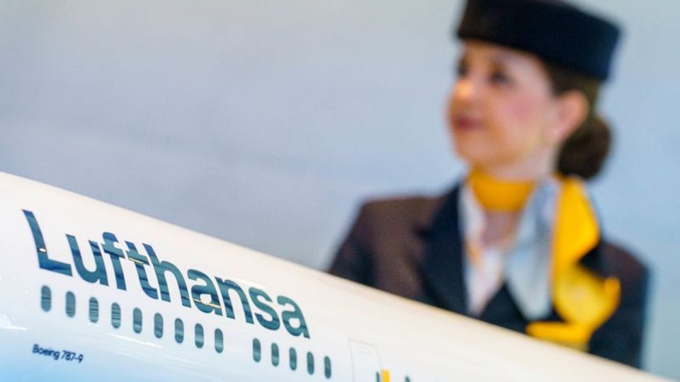 A Lufthansa employee stands in front of a model airplane