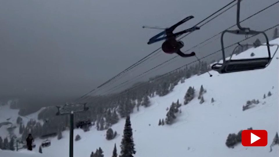 A skier flies through the air and gets stuck on a chairlift