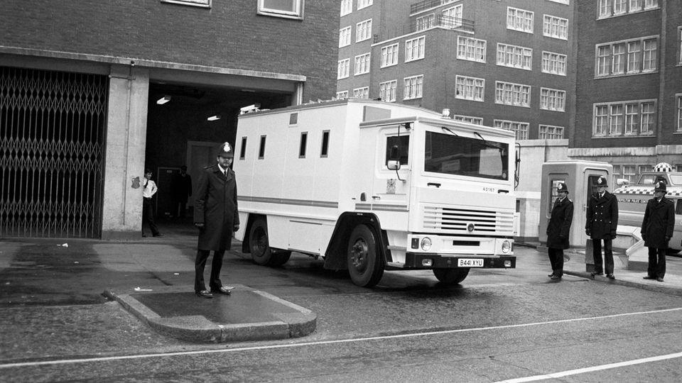 A white van in a black and white photo, an English police officer can be seen in the foreground