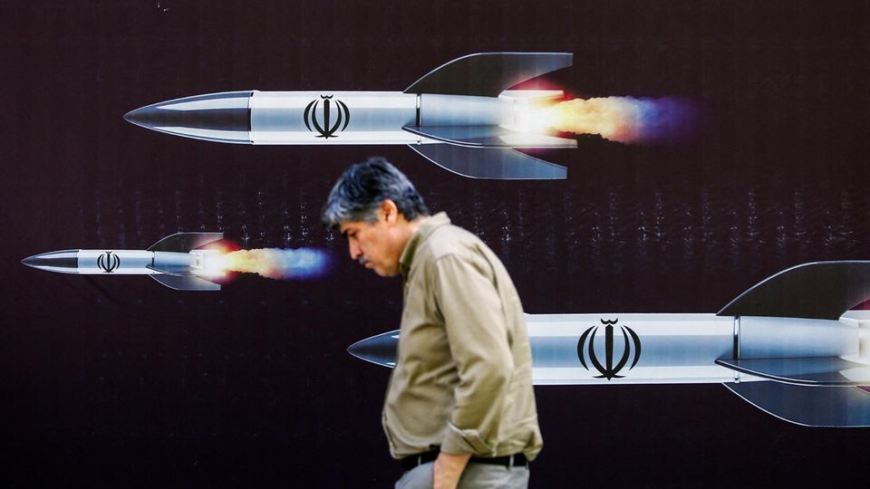 A man in Tehran walks in front of a poster of Iranian missiles