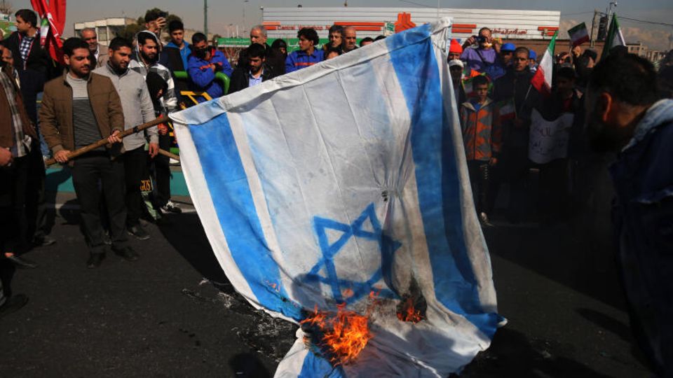 People in Iran burn an Israeli flag