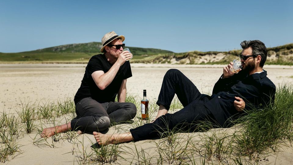 stern reporter Herrmann and his friend drink whiskey in Machir Bay