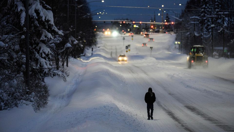 Man walking along snow-covered road in Anchorage, Alaska