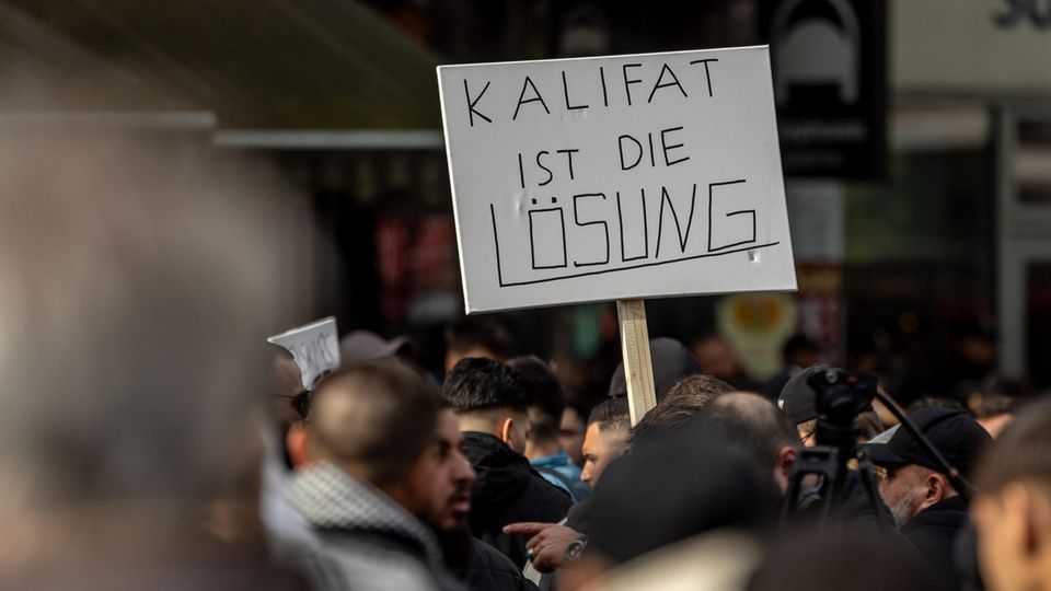 Participants of an Islamist demonstration hold a poster with the inscription "Caliphate is the solution" upwards