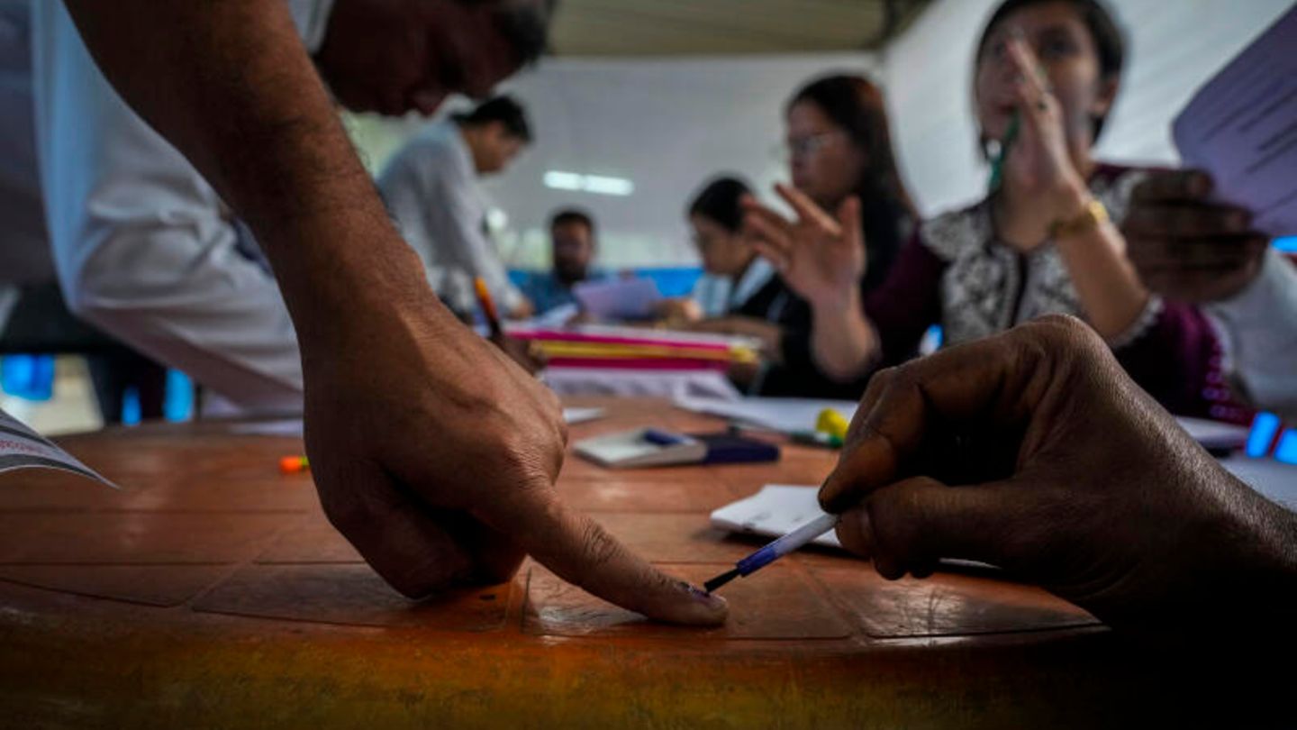 A poll worker marks a government official's finger with ink