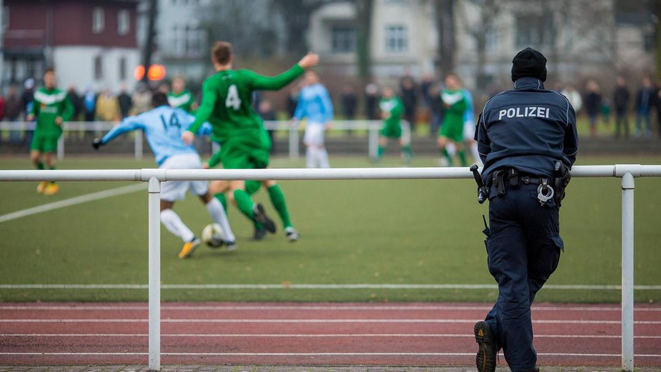 A police officer watches an amateur soccer game