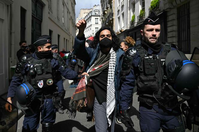 A protester is escorted during the evacuation of a sit-in in the entrance hall of Sciences Po Paris, May 3, 2024.