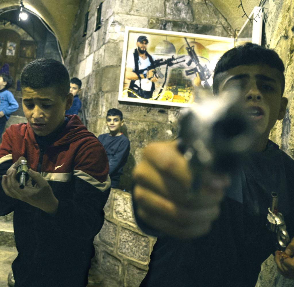Children play with toy guns in front of the house of a leader of a well-known militia in Nablus